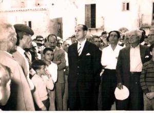Festeggiamenti in piazza per il Centenario dell'Unità d'Italia. Il sarto in camicia bianca è alla destra di un illustre, personaggio; a sinsitra un giovane dottore Luparelli